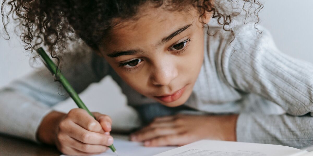 Niño concentrado escribiendo con lápiz en su cuaderno